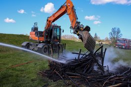 Graafmachine schiet brandweer te hulp bij brand in houtstapel voor insecten